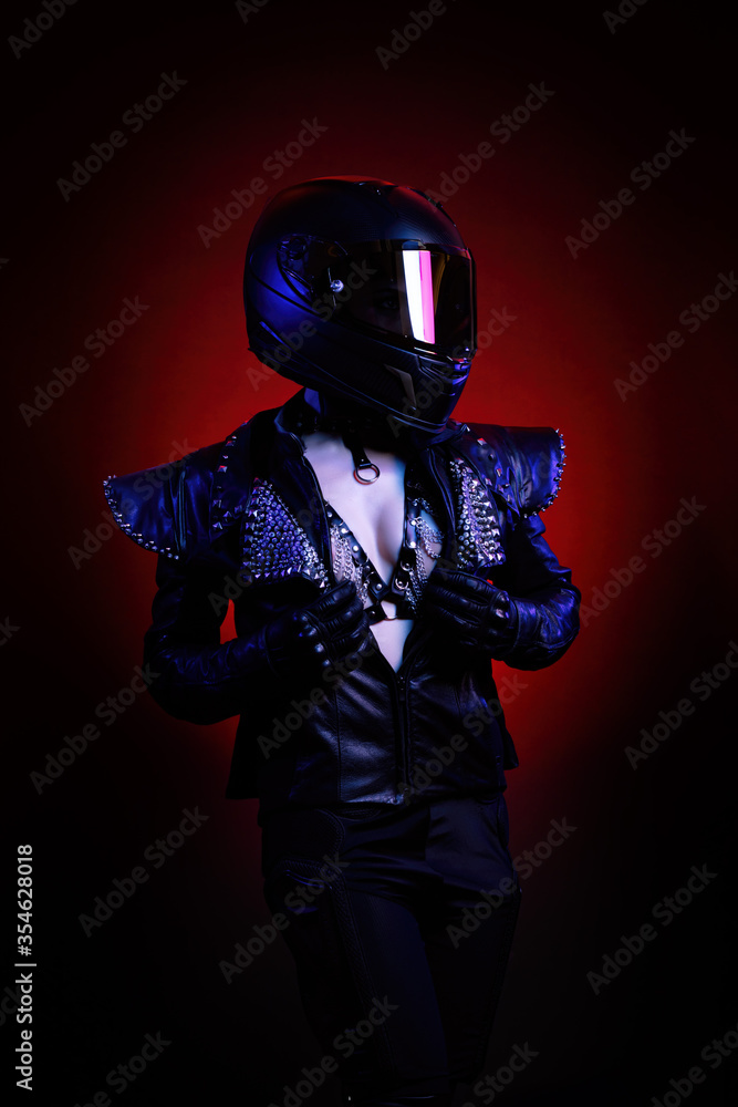 Portrait of a young sexy biker woman wearing a studded leather jacket and black helmet