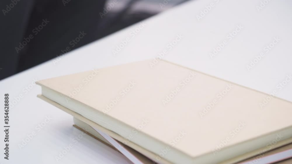 Female hand reaching to pick up her cellphone from top of the books Female hand reaching to pick up her cellphone from top of the books