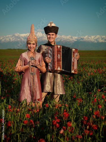 Kazakh musicians man and girl play on cheese and syzsykna in the field of red poppies photo