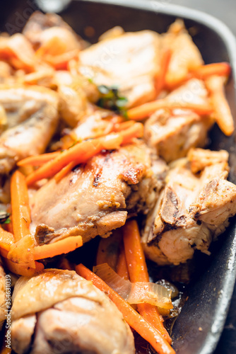 Roasted chicken on the pan with carrot, onion, gralic and other spices. Selective focus. Shallow depth of field.  photo