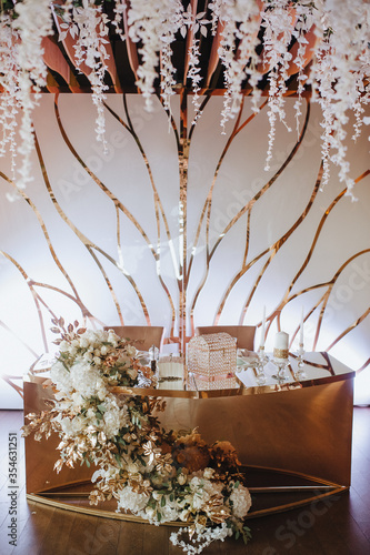 Banquet white table, presidium, candles, composition of flowers of pink, blue, lilac, white, rose, hydrangea, golden leaves, wisteria. Candles, crystal.