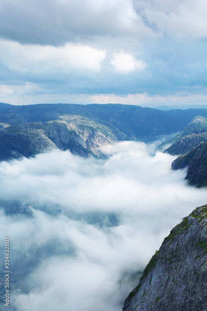 View of a deep valley in a fjord called Lysefjord in Norway covered by clouds. The view from the famous Kjerag trail.