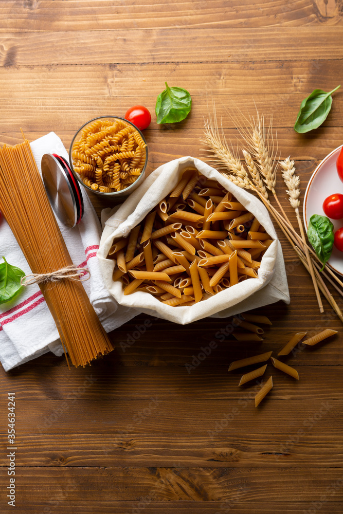 Uncooked wholegrain macaroni on wooden table top view Uncooked wholegrain macaroni on wooden table top view