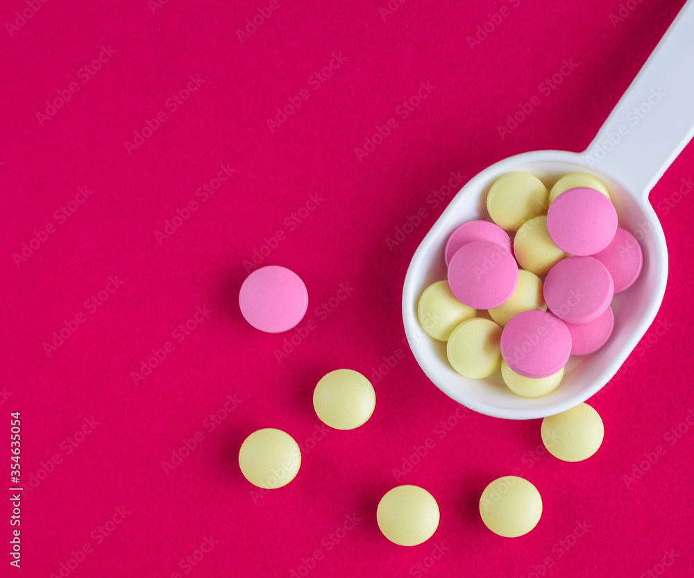 Colored pills on the table. Medical preparations on a pink background. Place for text. Colored pills on the table. Medical preparations on a pink background. Place for text.