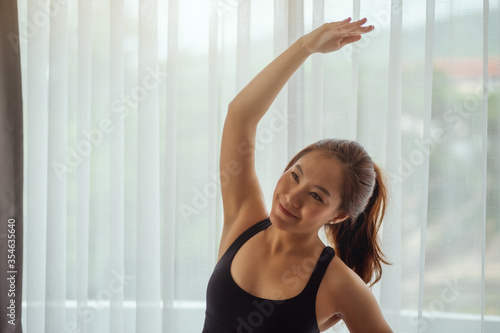 Closeup image of a beautiful young asian woman stretching her arms to warm up before workout at home