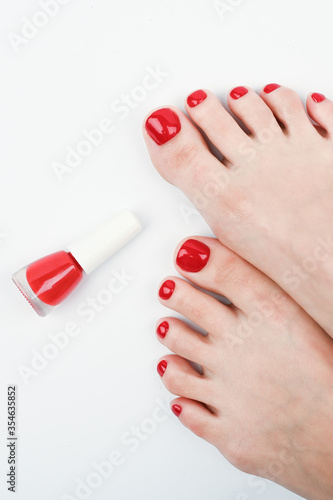 Female legs and red nail polish on a white background.