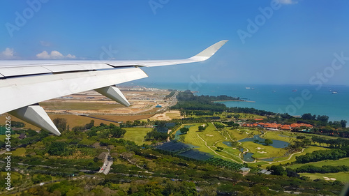 Wallpaper Mural Airplane wing in blue sky over the city over the golf course. Sea with ships in the background. Concept of travel and tourism Torontodigital.ca