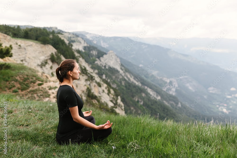 pregnant girl doing yoga or meditating, in the mountains, in the park or outdoors in the afternoon