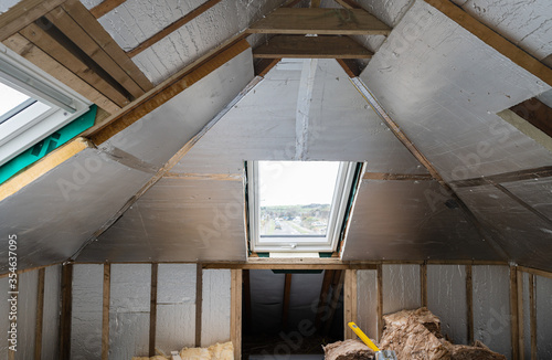 Loft conversion, unfinished project, silver insulation, roof windows, wood structure of the walls, selective focus