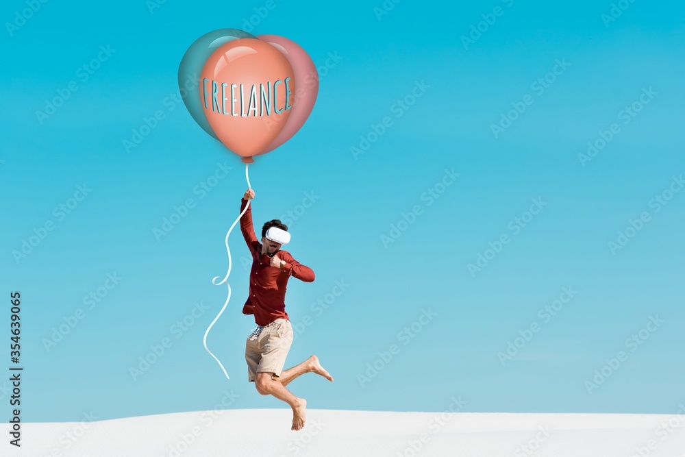 man on sandy beach in vr headset flying on balloon with freelance lettering against clear blue sky man on sandy beach in vr headset flying on balloon with freelance lettering against clear blue sky