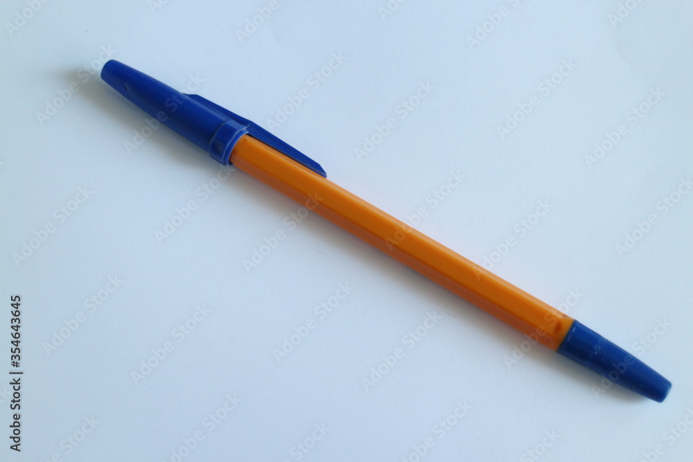 Fototapeta premium orange pen with a blue cap on a white table