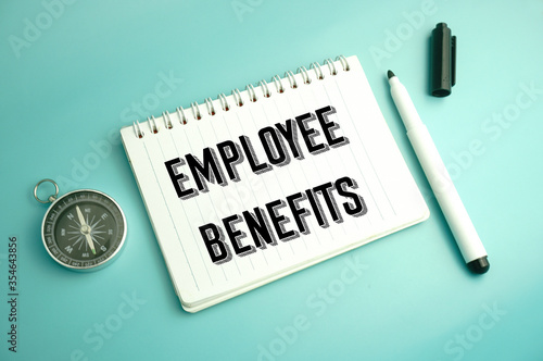 compass,marker pen and notebook written employee benefits over blue background.