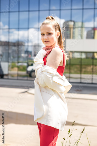 young blonde schoolgirl in a red suit and a white jacket posing in the parking lot © hiv360