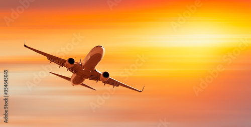 White passenger airplane in the clouds at sunset - Travel by air transport