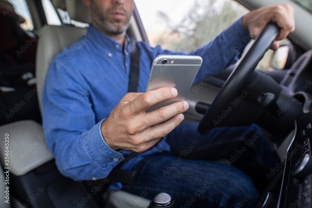 Hombre joven usando el teléfono móvil mientras conduce Hombre joven usando el teléfono móvil mientras conduce