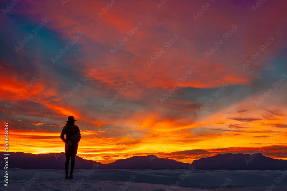 silhouette of a young woman in a cowboy hat reflecting on the sunset in White Sands National Par