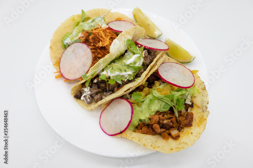 Three Tacos with Limes on a White Plate with a White Background