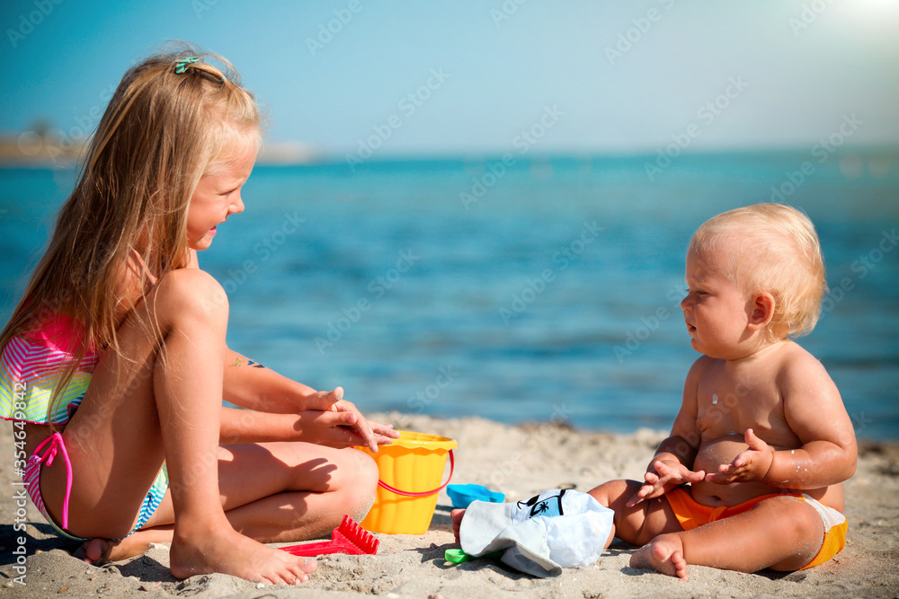 Children play on the beach. Summer water fun for the family. Boy and girl with toy buckets and a shovel on the seashore. Children play on the beach. Summer water fun for the family. Boy and girl with toy buckets and a shovel on the seashore.