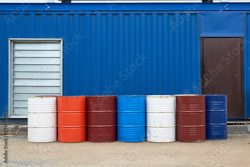 Standing in a row of old iron colored paint barrels. Blue garage with horizontal stripes.