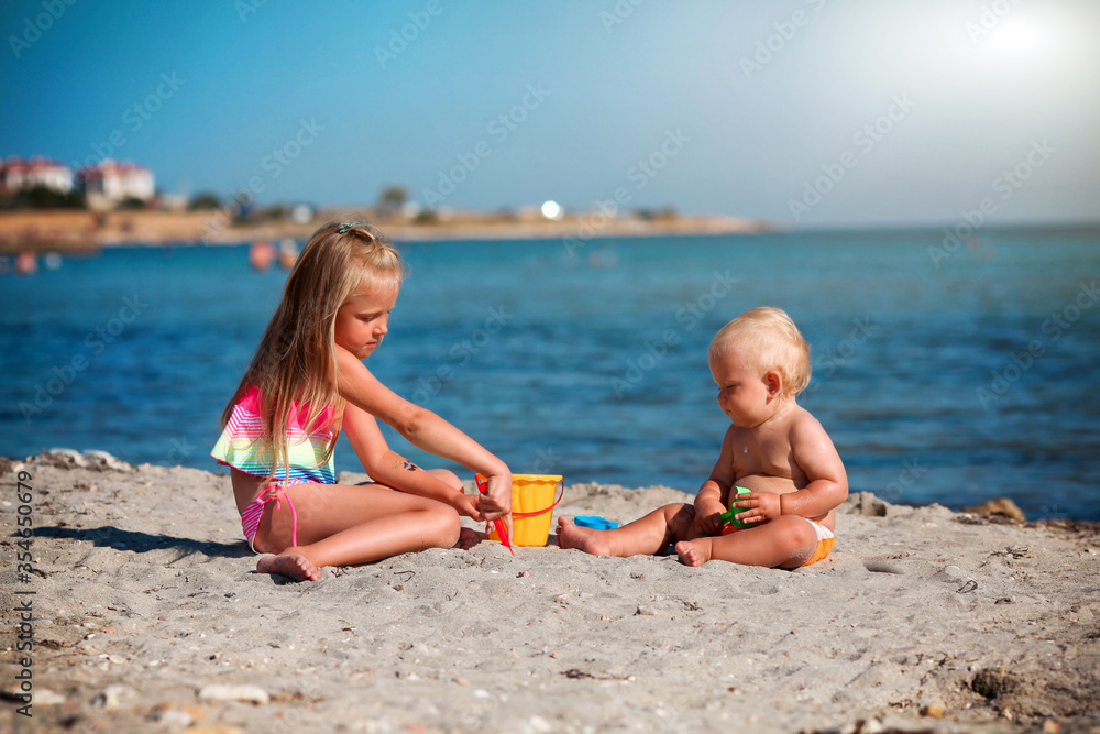 Children play on the beach. Summer water fun for the family. Boy and girl with toy buckets and a shovel on the seashore. Children play on the beach. Summer water fun for the family. Boy and girl with toy buckets and a shovel on the seashore.