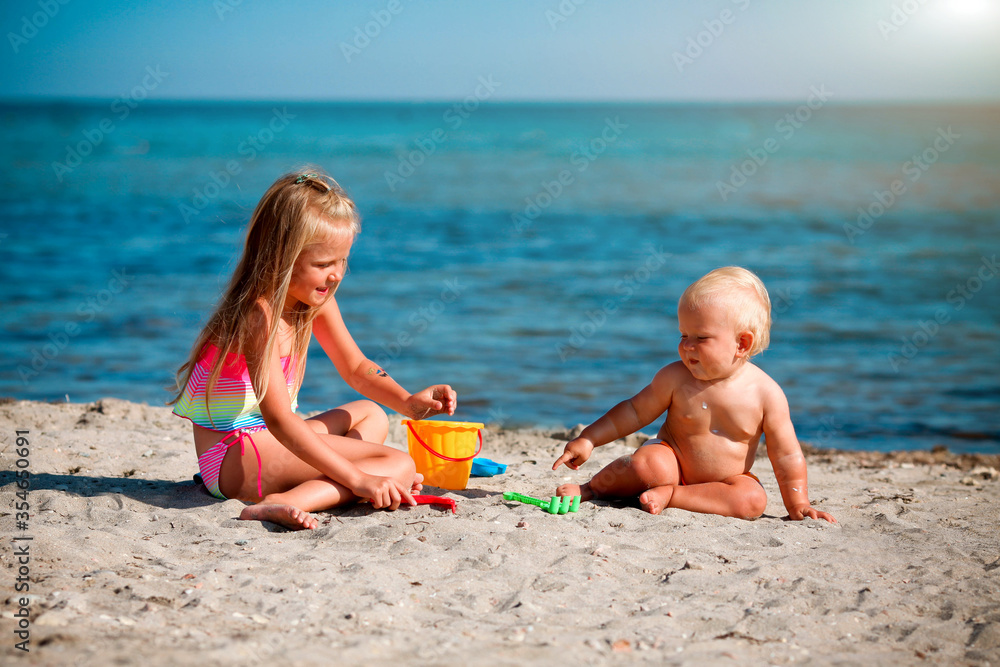 Children play on the beach. Summer water fun for the family. Boy and girl with toy buckets and a shovel on the seashore. Children play on the beach. Summer water fun for the family. Boy and girl with toy buckets and a shovel on the seashore.