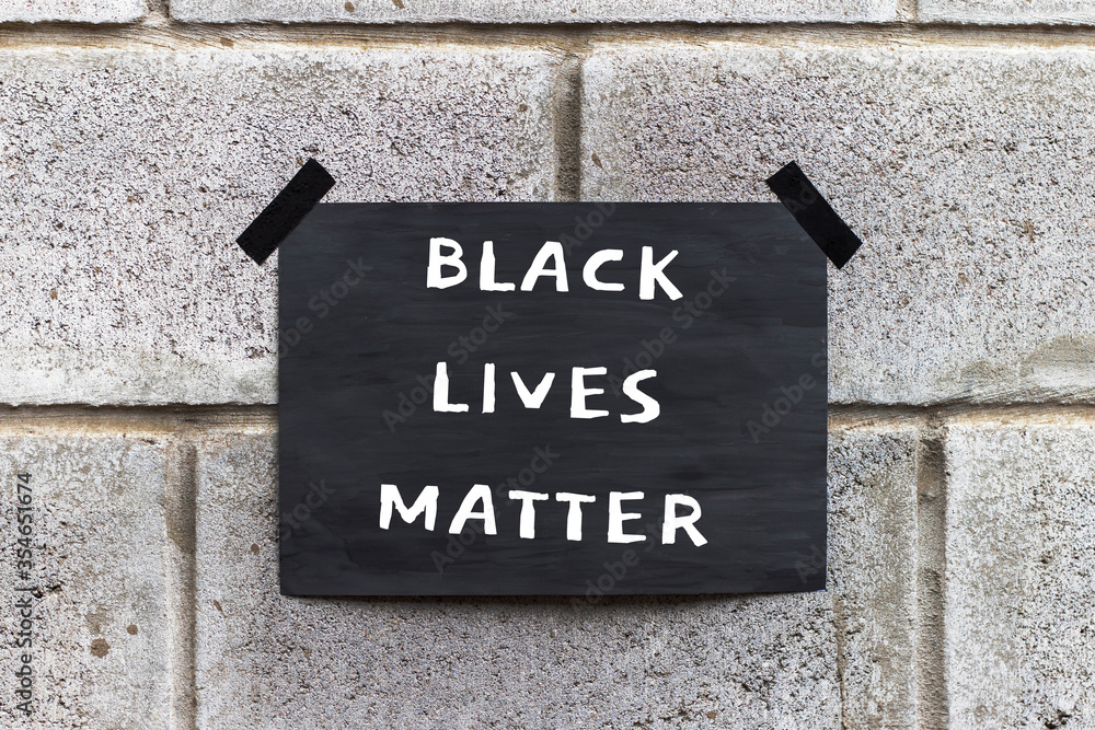 Obraz premium Black poster on gray brick wall. Banner with text Black Lives Matter. Anti-racism protest.