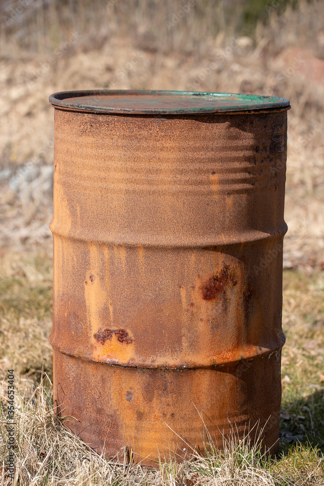 An old rusty barrel standing on dry grass An old rusty barrel standing on dry grass