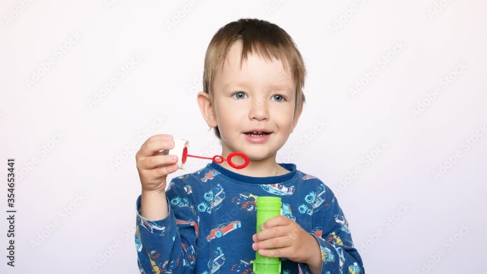 An attractive little boy blows some soap bubbles at the camera An attractive little boy blows some soap bubbles at the camera