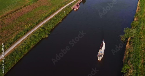 AERIAL: Man sailing on small sailboat in dutch canal in friesland holland top down with drone top down 4K/UHD