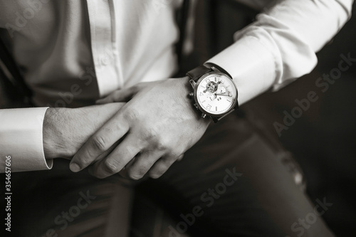 Men's wrist watch, the man is watching the time. Businessman clock, businessman checking time on his wristwatch. Groom's hands in a suit adjusting wristwatch, groom accessories