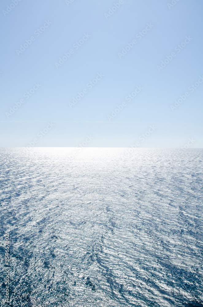 Seascape background of clear sky and vivid blue sea with sunlight reflection on surface
