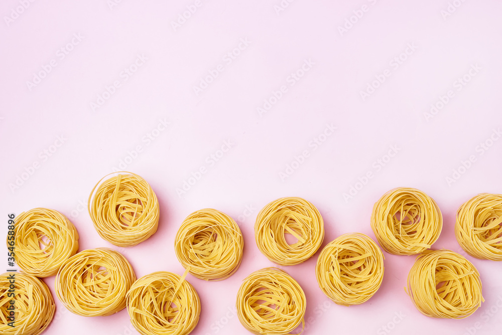 Fototapeta premium Group of Italian Egg Pasta Nest Tagliatelle Pink Background Italian Food Top View Copy Space