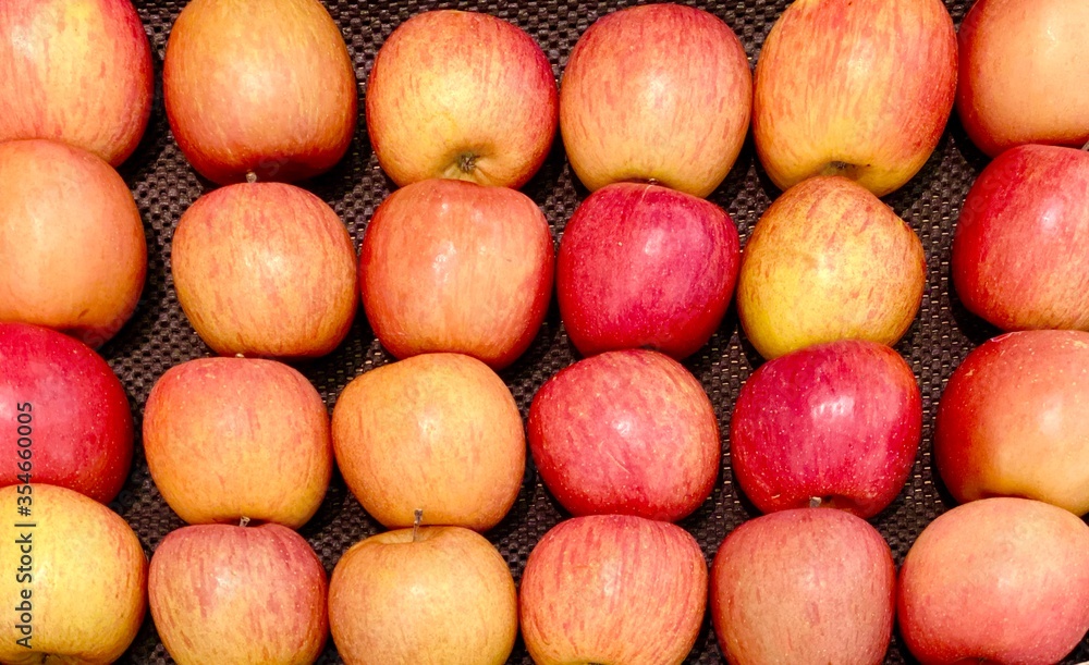 Close-up photo of apples (Cripps Pink) in market. Orderly rows fruits background. Texture red apple. Close-up photo of apples (Cripps Pink) in market. Orderly rows fruits background. Texture red apple.
