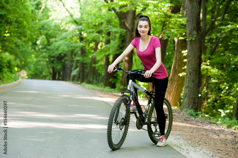 Female cyclist on a bike on asphalt road in the forest