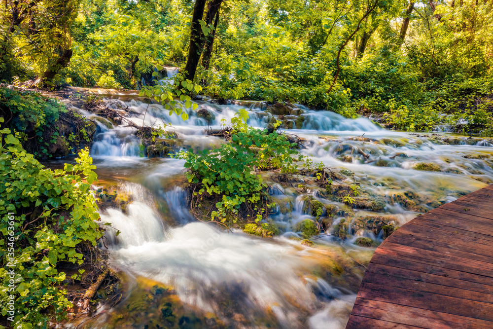 Wonderful summer view of Skradinski Buk waterfall with wooden bridge. Bright morning scene of Krka National Park, Lozovac village location, Croatia, Europe. Beautiful world of Mediterranean countries.