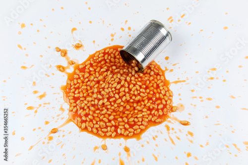 Obraz na płótnie Baked beans splattered in a mess with a tin on a white background