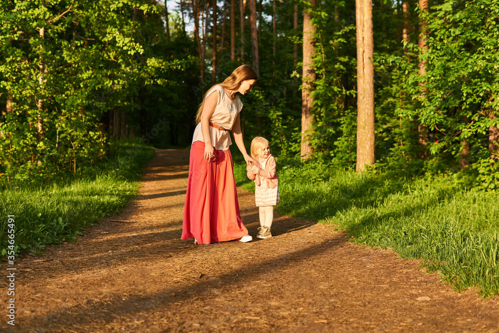 mother and daughter walk along a path in a park