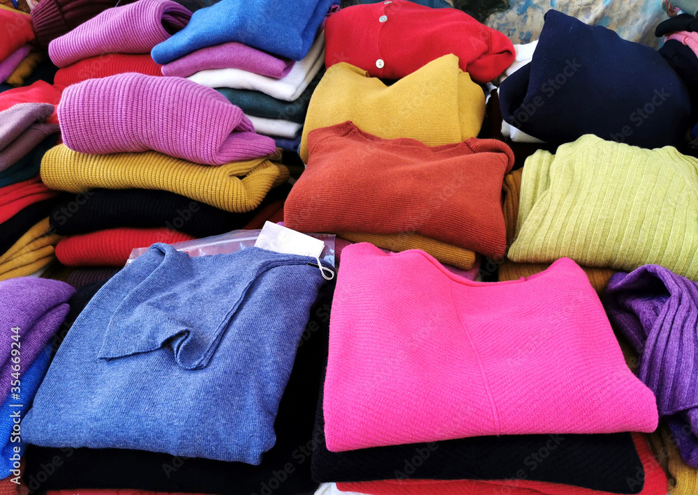 Generic colourful cashmere folded pullovers sweaters on an outdoors market stall shop stand. Affordable cheap modern elegant fashion wool casual style fabric garments clothing