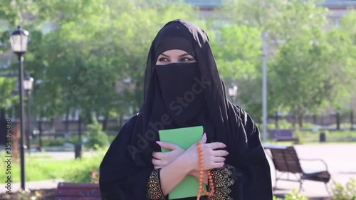 An Islamic woman in national women's clothing holds a holy book with prayers in her hands. photo