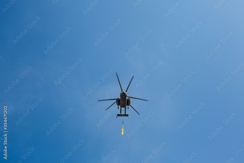 Small civil helicopter with Ukrainian flag flies against a blue sky with clouds background Small civil helicopter with Ukrainian flag flies against a blue sky with clouds background