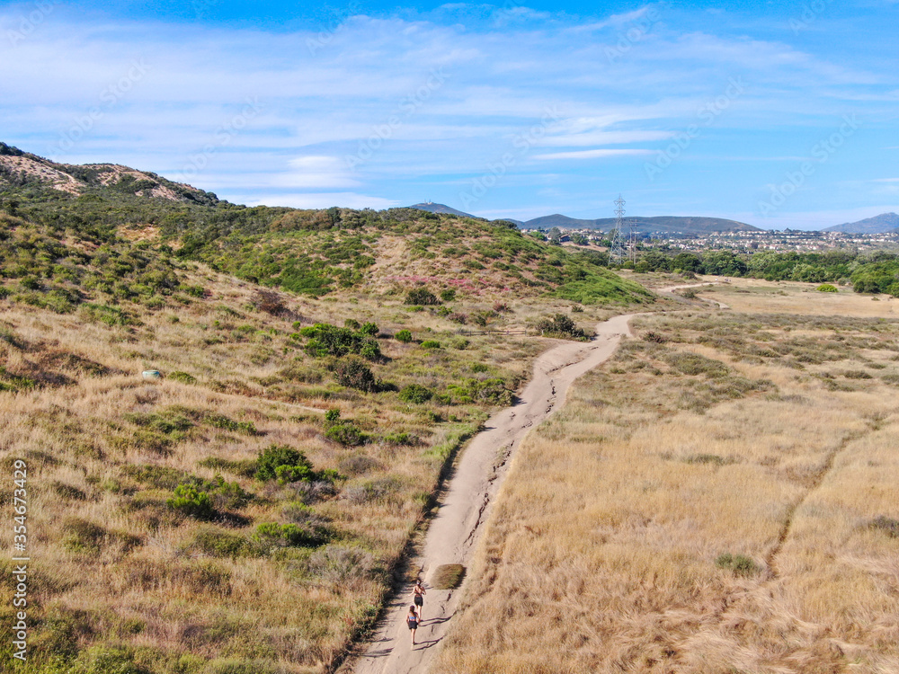 Aerial view of Los Penasquitos Canyon Preserve with tourists, hikers and bikers on the trails,. Urban park with mountain, forest and trails in San Diego, California. USA