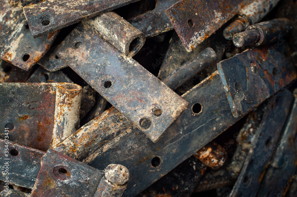 Background from heaps of old rusty metal door hinges. Selective focus. Raw materials for metal recycling