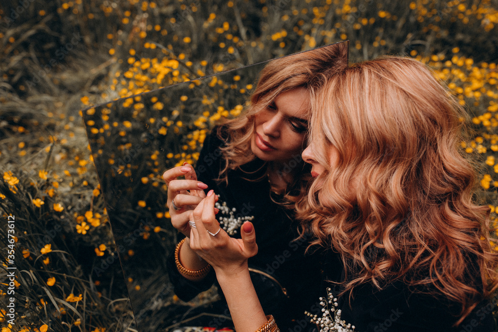 Photo session of a stylish girl outdoors with a mirror. Young model on a background of yellow flowers.
Photo session of a stylish girl outdoors with a mirror. Young model on a background of yellow flowers.