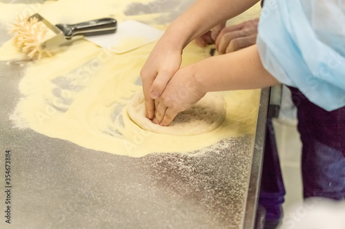 Children's hands prepare pizza, pizza dough