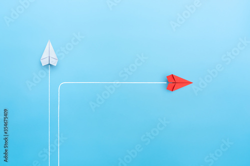 New normal concept with Red paper plane in new direction on blue background photo