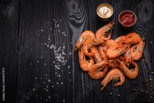 boiled shrimp with pepper, salt and sauces on a dark background
