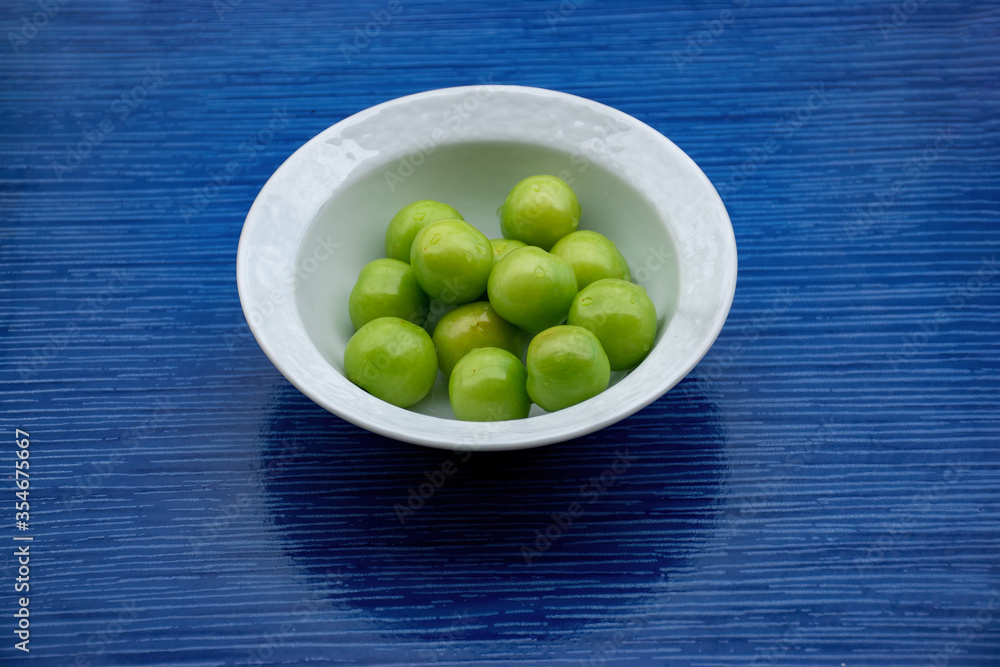 Fresh green plums harvested from tree in white bowl Fresh green plums harvested from tree in white bowl