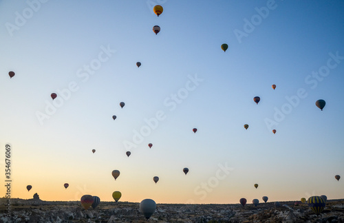 The sunrise in the mountains with Hot air balloons flying over Cappadocia red valley in the sky. Travel to Goreme, Turkey