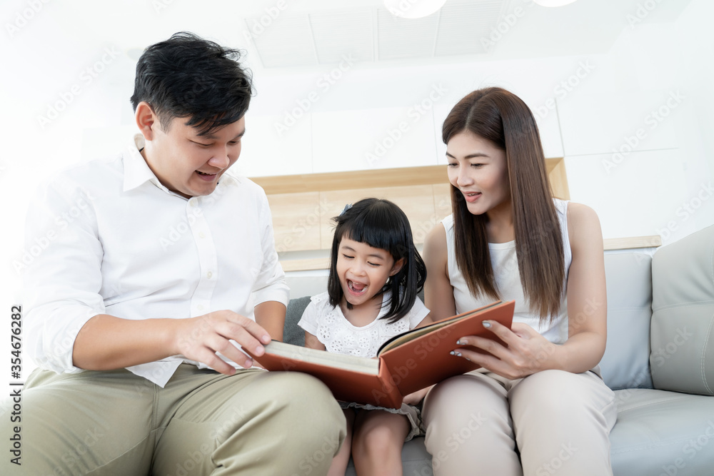 Asian family happy love to reading favorite book together, parents teach kids self learning at home in hobby time Asian family happy love to reading favorite book together, parents teach kids self learning at home in hobby time