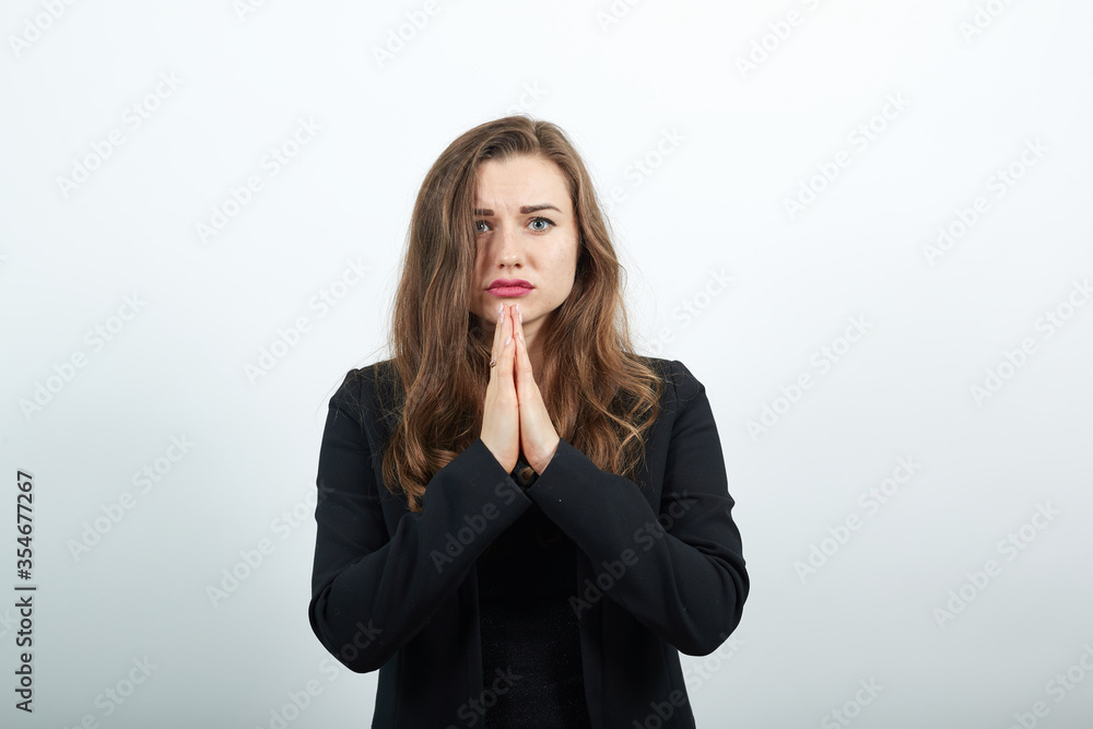 Folded hands together praying asking God for help ask implore wish upwards Jesus Christ, young attractive woman brunette in a black t-shirt and sweater on white background Folded hands together praying asking God for help ask implore wish upwards Jesus Christ, young attractive woman brunette in a black t-shirt and sweater on white background